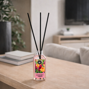 Dyfuzor zapachowy Strawberry Garden, różowy płyn, czarne patyczki, na drewnianym stole w salonie.