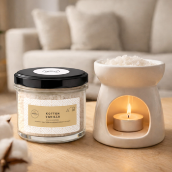 Biały ceramiczny kominek zapachowy z tealightem i słoik wosku Cotton Vanilla na drewnianym stoliku.