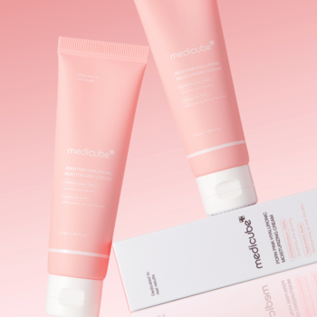 Dwie brzoskwiniowe tubki Medicube Red Cream i białe pudełko, widok pod kątem na różowym tle.