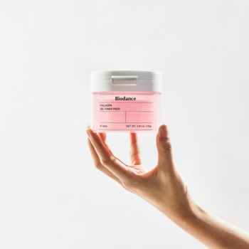 Ręka prezentuje różowe opakowanie Biodance Low Molecular Collagen z nawilżającymi żelowymi płatkami tonizującymi.