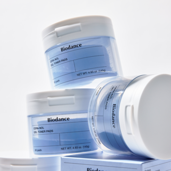 Biodance Ceranol Gel Toner Pads w trzech przezroczystych słoikach, niebieskie etykiety, dynamiczne ujęcie.