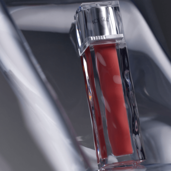 Muzigae Mansion Icy Glow błyszczyk Slay w przezroczystej tubie z koralowym płynem, widok pod kątem.