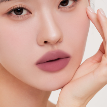 Zbliżenie na usta z tintem Muzigae Mansion Appeal. Matowy, różowo-fioletowy kolor, lekki żelowy tint.