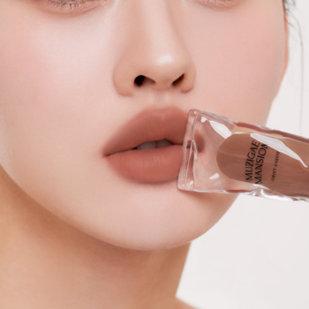 Zbliżenie na usta z matowym tintem Muzigae Mansion Pride w brązowym odcieniu, z przezroczystym aplikatorem.