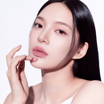 Modelka prezentuje lekki żelowy tint do ust Muzigae Mansion Whisper o matowym wykończeniu. Zbliżenie.