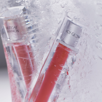 Dwa błyszczyki Muzigae Mansion Icy Glow Prim, czerwono-różowe, zanurzone w wodzie z lodem, z bliska.