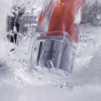 Błyszczyk Muzigae Mansion Icy Glow Tannin zanurzony w wodzie, ukazujący krystaliczny blask i ultra-nawilżenie.