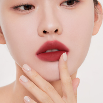 Lekki tint do ust Muzigae Mansion Dominant, zbliżenie na usta z matowym, głębokim czerwonym kolorem, palec dotyka wargi.