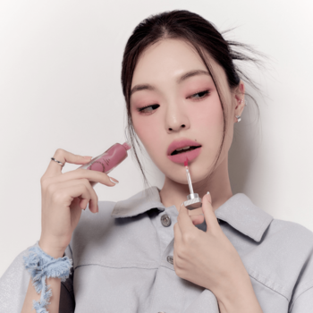 Kobieta aplikuje matowy tint do ust Muzigae Mansion w odcieniu Behind. Zbliżenie na produkt i usta, jasnoróżowy kolor.