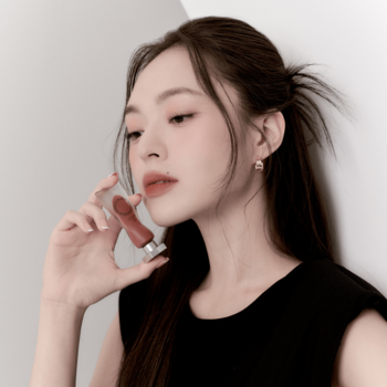 Muzigae Mansion Rare matte tint do ust w dłoni modelki, widok z bliska na buteleczkę z brązowym odcieniem.