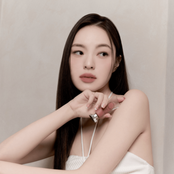 Muzigae Mansion matowy tint do ust w odcieniu Pitch, trzymany przez modelkę przy twarzy. Zbliżenie na produkt i usta.