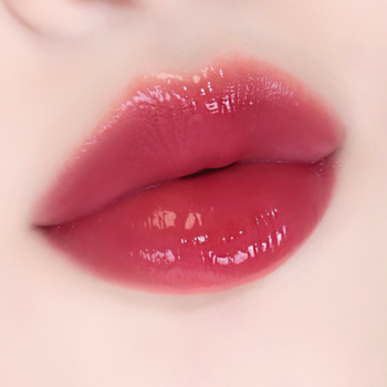 Zbliżenie na usta z malinowym błyszczykiem o lśniącym wykończeniu. Delikatnie rozchylone, pełne blasku.