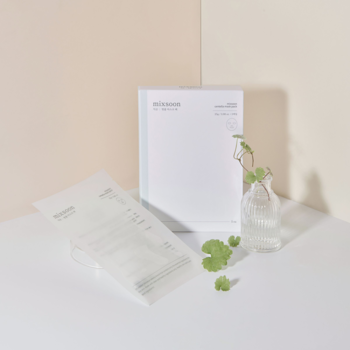 Nawilżająca maseczka Mixsoon Centella Mask Pack, białe opakowanie z rośliną i ulotką na pastelowym tle.