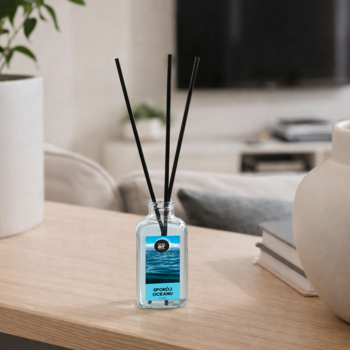 Dyfuzor zapachowy 'Naturally Scented' z niebieskim płynem i czarnymi patyczkami, na drewnianym stole w salonie.