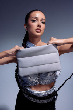 Szara, pikowana kosmetyczka typu puff, prostokątna i miękka w dotyku, trzymana przez kobietę.