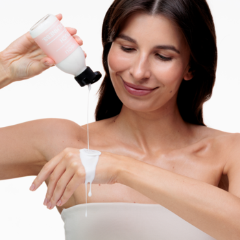 Mleczny tonik do twarzy Veoli Botanica Touch Of Calmness, wylewany z białej butelki na dłoń kobiety.