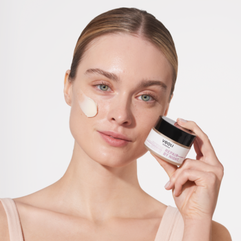 Kobieta z nałożonym kremem Veoli Botanica Repair By Night na policzku, trzyma słoiczek. Regenerujący krem na noc.