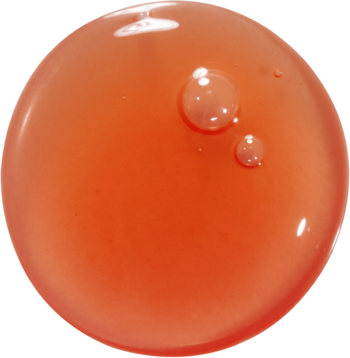 Zbliżenie na błyszczącą kroplę olejku do ust Kaja Juicy Glass Lip Oil Apricot Allure, o pomarańczowo-czerwonym odcieniu.