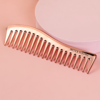 Metaliczny grzebień ZURI Sister Young z szerokimi zębami, rose gold, na różowym tle, widok z góry.