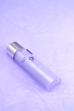 Liliowy tonik rozjaśniający Nutriquilizer 9+, butelka leżąca ukośnie na fioletowym, marmurowym tle.