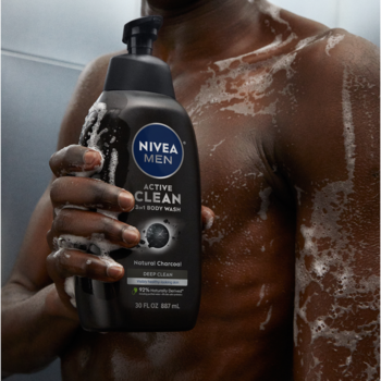 Czarny żel pod prysznic NIVEA MEN Active Clean 3w1 z węglem, trzymany przez spienionego mężczyznę pod prysznicem.