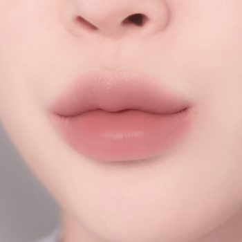Zbliżenie na miękkie, pełne usta z matowym, pudroworóżowym wykończeniem pomadki, podkreślające ich naturalny kształt.
