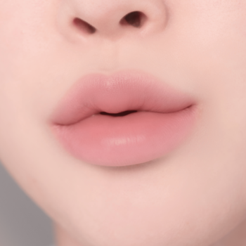 Zbliżenie na pełne, delikatnie różowe usta z matowym wykończeniem, w naturalnym odcieniu nude.