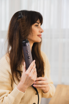 Kobieta kręci włosy suszarko-lokówką Beautifly Flow Pro Styler, która automatycznie nawija pasmo.