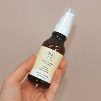 Łagodząca esencja do twarzy Barr z Centella Asiatica, brązowa butelka z białą pompką, trzymana w dłoni.