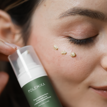 Zbliżenie: krem Polemika z matchą w trzech zielonkawych kropkach pod okiem. Kobieta testuje nawilżający krem pod oczy.