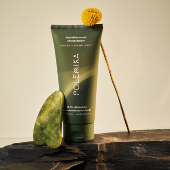 Polemika hydrofilne masło oczyszczające, zielona tuba, z gua sha i żółtym kwiatem na kamiennym blacie.