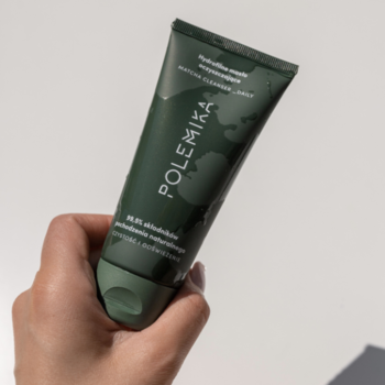 Ciemnozielone hydrofilne masło oczyszczające Polemika Matcha Cleanser w tubce, trzymane w dłoni.
