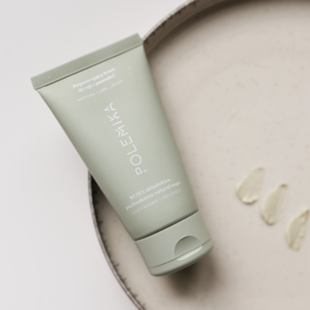 Zielona, matowa tubka Polemika Regenerującego kremu do rąk i paznokci na beżowej tacy, próbki kremu obok.