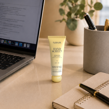 Żółta tubka nawilżającego kremu do rąk FlosLek Hand Screen Photo Age Shield SPF 20 na biurku z laptopem.