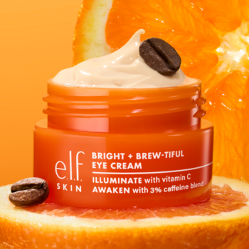 elf BRIGHT + BREW-TIFUL EYE CREAM, pomarańczowy słoiczek z kremem, ziarnem kawy, otoczony plasterkami cytrusów.