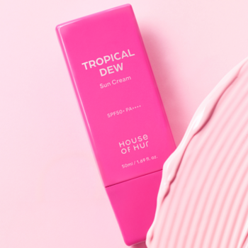 Różowy krem do opalania Tropical Dew SPF50+ PA++++ od House of Hut, ułożony ukośnie na różowym tle.