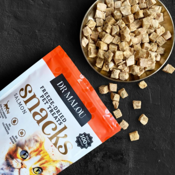 Dr Malou liofilizowany łosoś: pomarańczowa torebka z kotami i kostki łososia w misce na ciemnym tle.