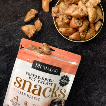 Dr Malou liofilizowane serca kurczaka dla psa i kota, otwarte opakowanie na czarnym tle z miską przysmaków.