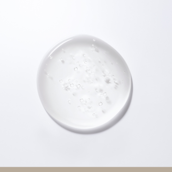 Zbliżenie na przezroczystą kroplę szamponu ICONIQUE Professional Repair & Strengthening z bąbelkami, na białym tle.