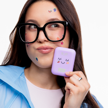 Kobieta w okularach z Fluff Juicy Patches na niedoskonałości, trzyma fioletowe etui z uśmiechniętą chmurką.