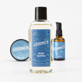 Zestaw Groomen AQUA do brody: szampon (centralnie), balsam i olejek na białym tle. Butelka szamponu z niebieską etykietą.