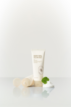 Dwie tubki kremu do twarzy Balancing Cica Centella Cream na białym tle, obok spieniony produkt i zielony listek.