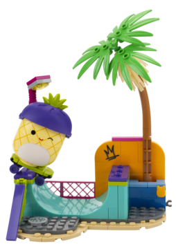 Zabawka LEGO: żółty ananas w fioletowej czapce wjeżdża na rampę skate parku z zieloną palmą. Widok z przodu.