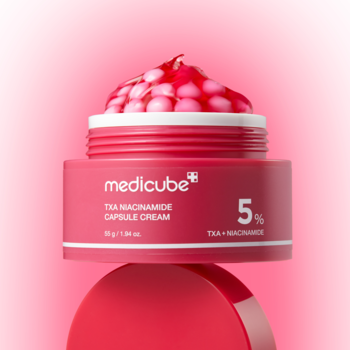 Różowy słoik Medicube TXA Niacinamide Capsule Cream z czerwonymi kapsułkami, widok z góry na intensywnie różowym tle.