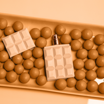 Sweet Tooth woda perfumowana S. Carpenter. Białe butelki z fakturą, otoczone karmelowymi pralinkami na pomarańczowej tacy.