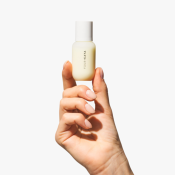 Mała, kremowa butelka regenerującego serum samoopalającego SELF-TAN DROPS w dłoni na białym tle.