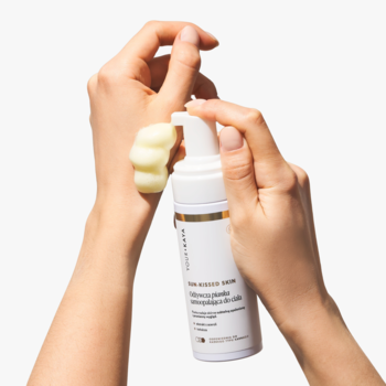 Dłoń wyciska jasnożółtą piankę samoopalającą SUN-KISSED SKIN z białej butelki na drugą dłoń do testu.
