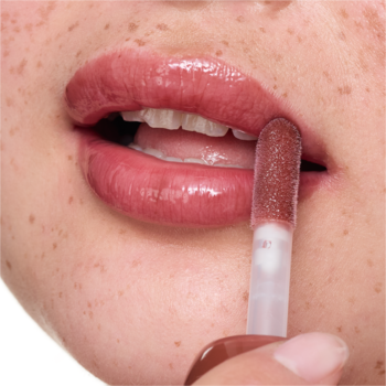 Zbliżenie: aplikator nakłada lśniący balsam do ust essence milky GLAZED 05 Latte-tude, odcień średniego brązu.