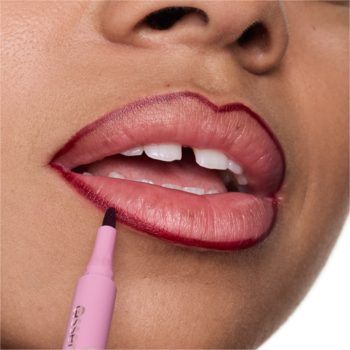Zbliżenie na usta kobiety, konturowane konturówką essence TATTOO LIP LINER 01 w odcieniu nude-pink. Widoczny aplikator.