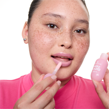 Kobieta nakłada lśniący, mleczny balsam do ust essence milky GLAZED 02 Strawberry Whip w pastelowym różu.